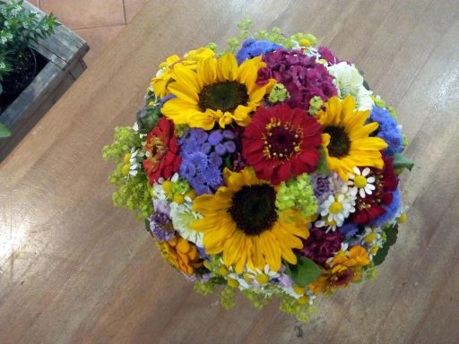 Bunte Blumenarrangement mit Sonnenblumen, Astern und weiteren farbenfrohen Blumen.