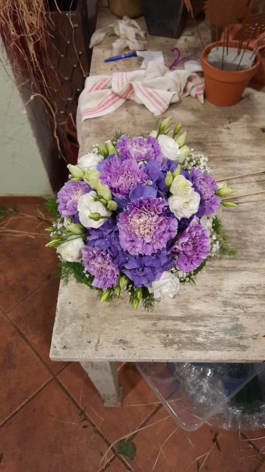 Bunter Blumenstrauß aus lila und weißen Blumen auf einem Holztisch.