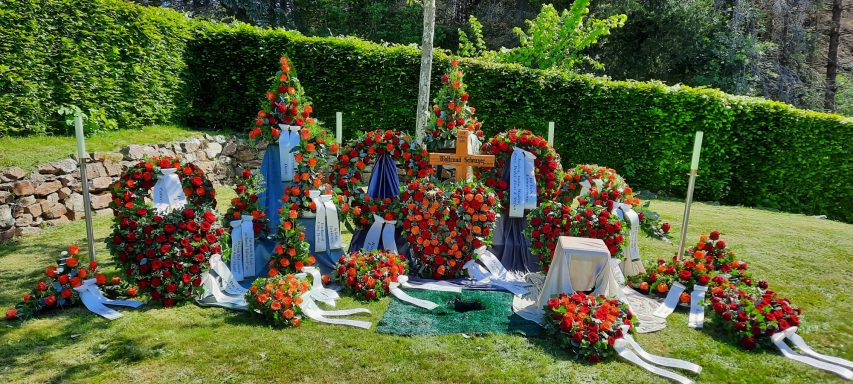 Vielfältige Blumenkränze und -arrangements auf einer grünen Wiese.