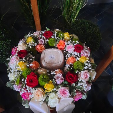 Bunte Blumenkranz mit Rosen, Schleierkraut und einer zentralen Dekoration.