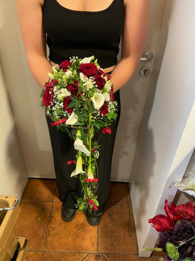 Eine Person hält einen bunten Blumenstrauß mit roten und weißen Blumen.