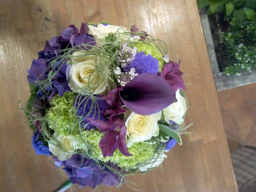 Bunte Blumenarrangement mit Violett- und Grüntönen, darunter Calla und Rosen.